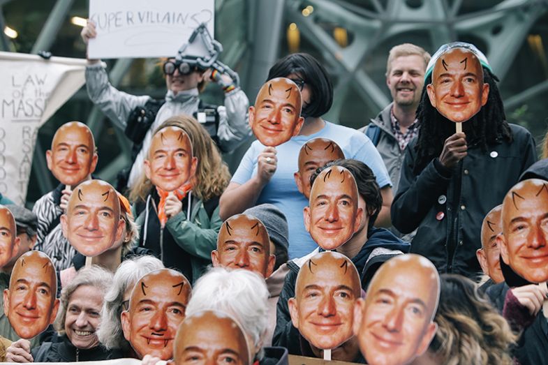 people wearing Jeff Bezos masks with devil horns drawn on