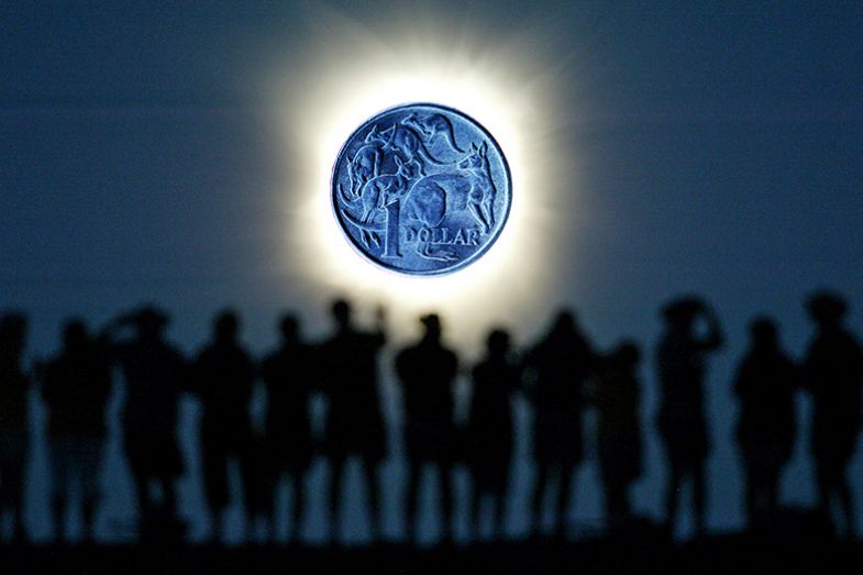 Tourists watch the sun being blocked by the moon during a solar eclipse in the Australian outback town of Lyndhurst, with a dollar coin instead of the moon. To illustrate how Australia's funding system could diminish blue-sky research.