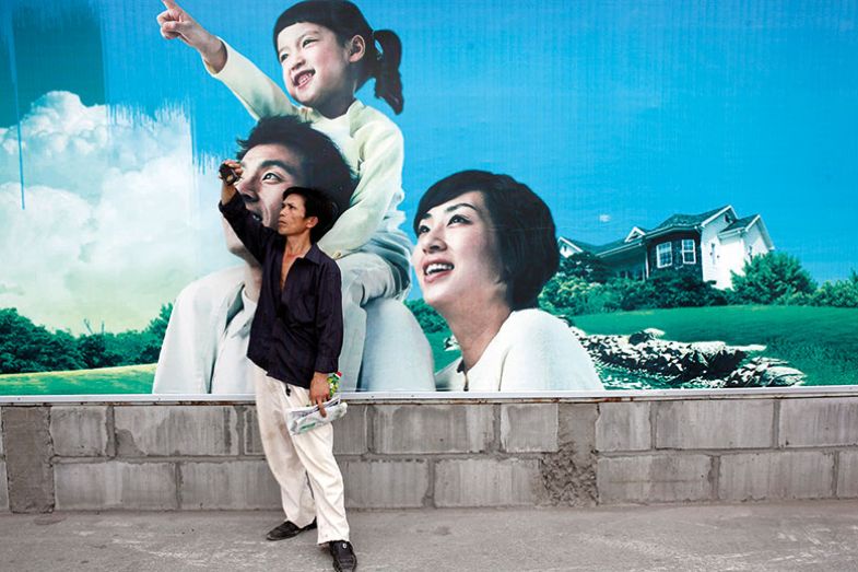 Man takes photo in front of poster of one-child family, Shanghai, China
