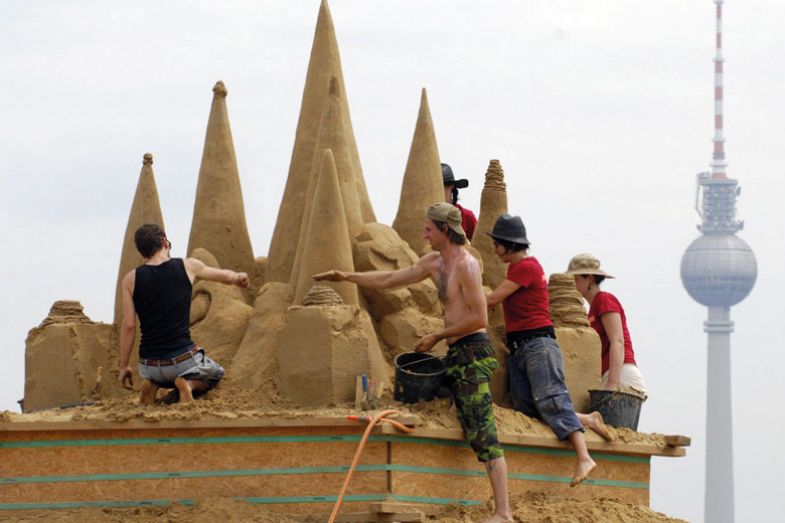 sand carvers  work on their piece in front of Berlin's landmark TV tower