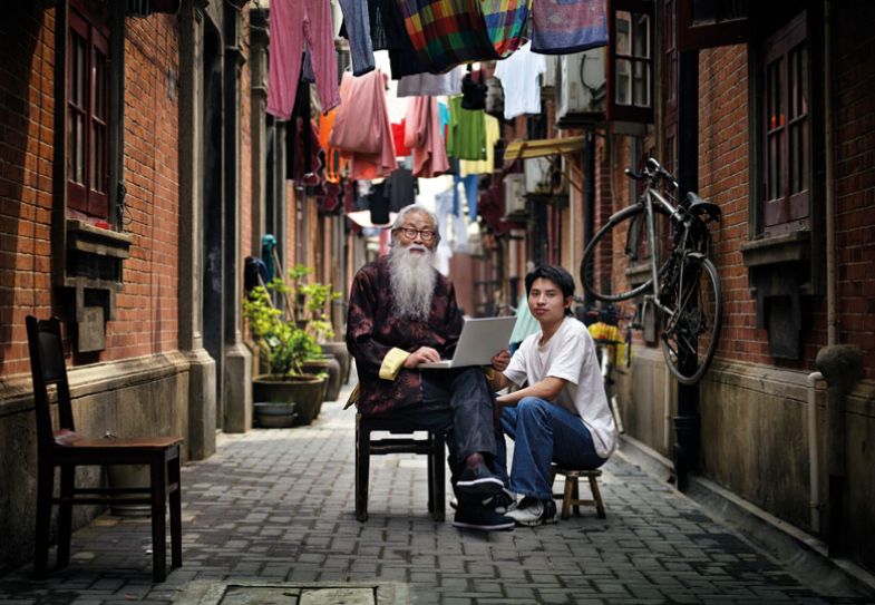 Elderly Chinese Man and Young Chinese Man with Laptop in Alley to illustrate older people learning