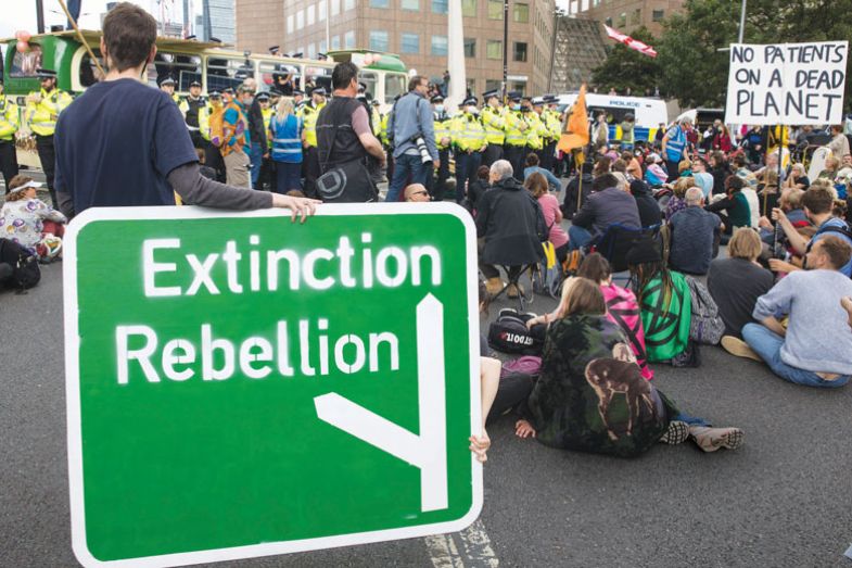 Protestor holding large Extinction Rebellion road sign during a protest 