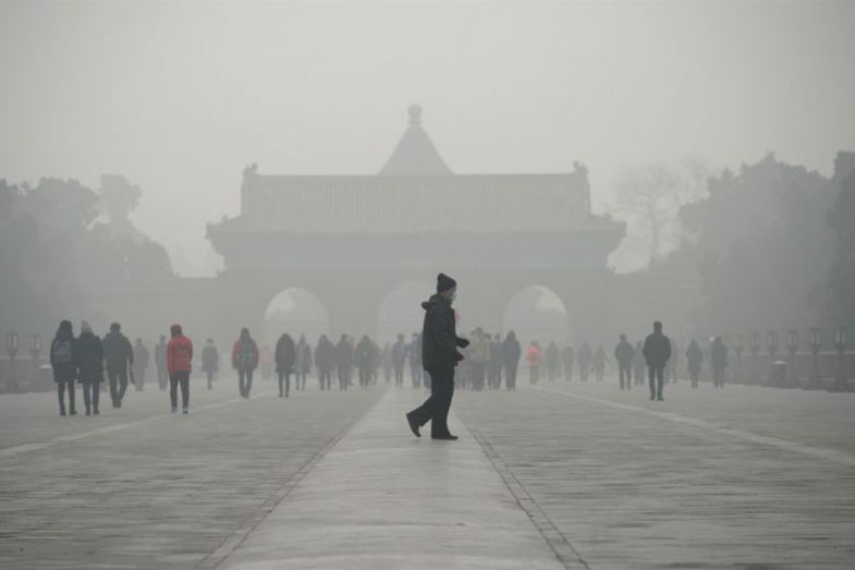 A man walks in front of a group of people during heavy smog at a the Temple of Heaven park in Beijing