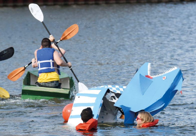 Teams compete during the Rock the Boat cardboard boat race with a lady in the water Teams compete during the Rock the Boat cardboard boat race with a lady in the water to illustrate Sinking or swimming