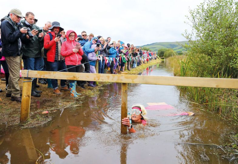 Lady in middle of muddy river taking part in the World Bog Snorkelling Championships to illustrate Constrained by outdated policies