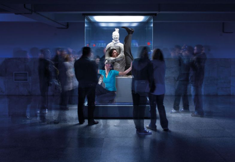 Crowd of tourists surrounds a statue of a terracotta archer with two people inside the statue Crowd of tourists surrounds a statue of a terracotta archer