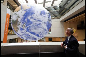 A man looks at a giant globe A man looks at a giant globe