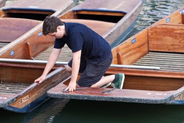 A boy working on the punts at the University of Cambridge A boy working on the punts at the University of Cambridge