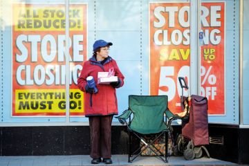 A charity collector standing outside a shop