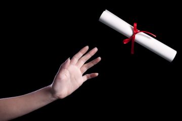 A hand reaching out to take a rolled up copy of a degree certificate A hand reaching out to take a rolled up copy of a degree certificate