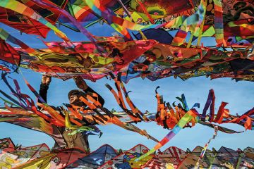 A man surrounded by colourful kites A man surrounded by colourful kites