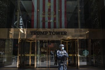 A counter-terrorism officer wearing a face mask stands at the entrance of Trump Tower