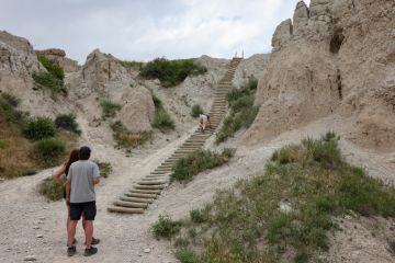 A hiker climbing the ladder of the Notch Trail at Badlands National Park, South Dakota A hiker climbing the ladder of the Notch Trail at Badlands National Park, South Dakota