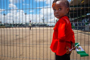 A young girl was seen holding Nigeria Flag behind a barricade during 62nd independence day celebration at eagle square, Abuja, Nigeria