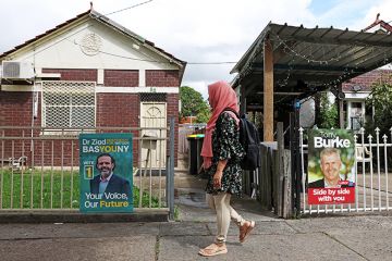 A woman walks past campaign signs depicting candidates in Lakemba, Australia, 12 March 2025. 