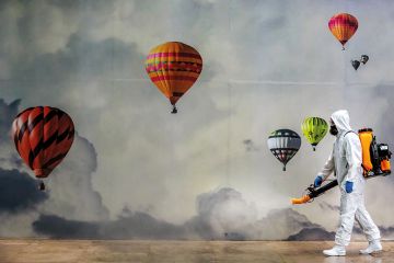 Man in PPE surrounded by hot-air balloons