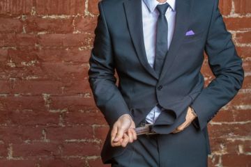 A suited man tightens his belt