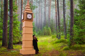 Graduate leaning on model of Big Ben in forest Graduate leaning on model of Big Ben in forest