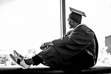 A black college graduate looks out of the window