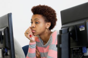 Bored young woman looking at computer screen Bored young woman looking at computer screen