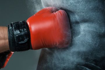 Boxer's hand punching heavy bag
