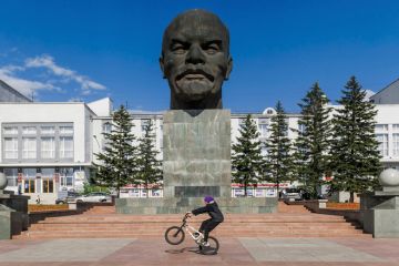 Boy riding BMX in front of bust of Vladimir Lenin Boy riding BMX in front of bust of Vladimir Lenin