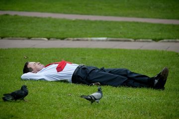 Sleeping businessman in a park on his lunch break, illustrating that employers are taking a back seat with regard to funding higher education. 