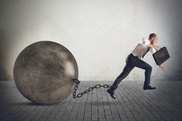 Businessman running with ball and chain on ankle Businessman running with ball and chain on ankle