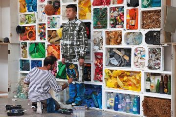 Camouflage artist Liu Bolin at the Surfrider Foundation in Biarritz, blended into a background of rubbish, 2017 Camouflage artist Liu Bolin at the Surfrider Foundation in Biarritz, blended into a background of rubbish, 2017
