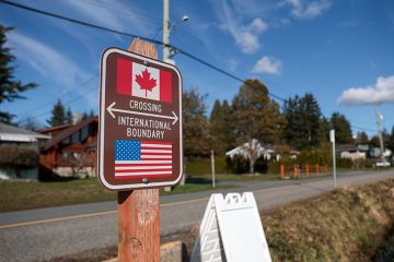 A sign marking the international border between the United States and Canada is pictured at Peace Arch Historical State Park in Blaine, Washington