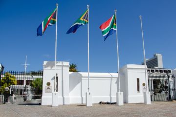 A homeless person sleeping under the South Africa flag at the Cape Town Parliament