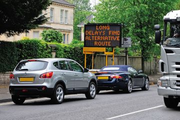 Cars in traffic jam with 'Long delays, find alternative route' sign Cars in traffic jam with 'Long delays, find alternative route' sign