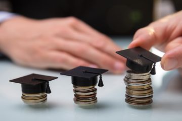 Hand Placing Graduation Hat Over Stacked Coins In A Row