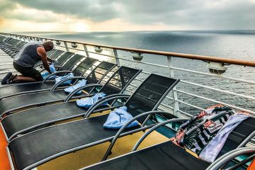 A man puts a towel on a lounger on the deck of a ship