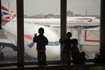 Children looking at British Airways planes out of an airport window. To illustrate the UK banning dependants. Children looking at British Airways planes out of an airport window. To illustrate the UK banning dependants.