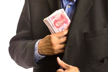 A businessman pocketing Chinese banknotes A businessman pocketing Chinese banknotes
