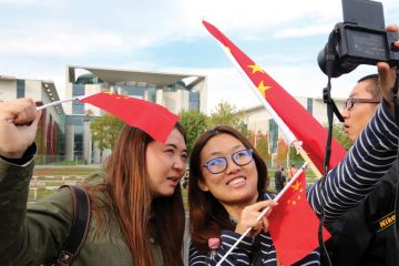 Two women take a selfie with Chinese flags