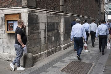 A man watching workers walk away from him in London. To illustrate that graduates can be better off than those without degrees. A man watching workers walk away from him in London. To illustrate that graduates can be better off than those without degrees.