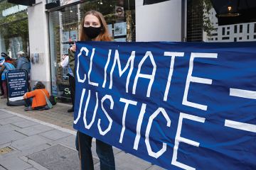Woman holding climate justice protest banner Woman holding climate justice protest banner