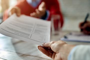 Close-up of job applicant giving his resume during job interview in the office.