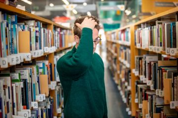 A man looks confused in a library aisle