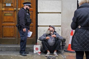 A police officer speaking with a man illegally busking on the recorder, Brick Lane, London