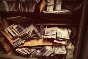 Rolls of banknotes stashed in a safe, symbolising corruption