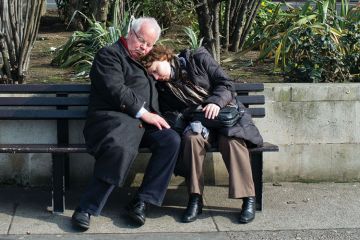 Couple sleeping on bench in London