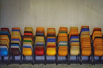 Colourful set of chairs piled up by a wall Colourful set of chairs piled up by a wall
