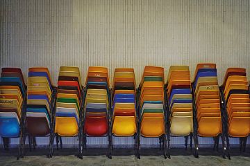 Colourful set of chairs piled up by a wall
