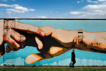 Man walking past mural of clasped hands Man walking past mural of clasped hands