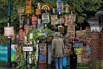 A member of the public walks past a display of signs relating to Covid