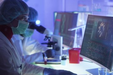 Scientists in protective suits look at Covid images online