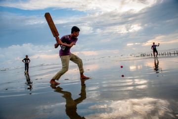 Boys play cricket on the beach